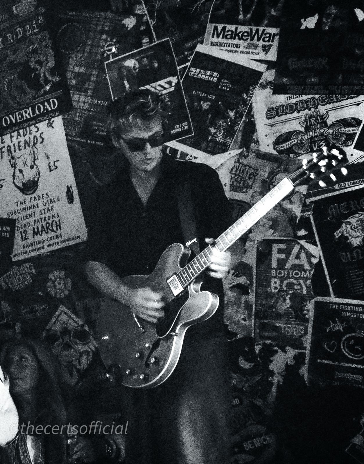 Guitarist against a wall of gig posters